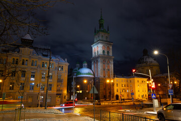 Fototapeta premium night time scene city street with church tower buildings road traffic long exposure Europe district historical view
