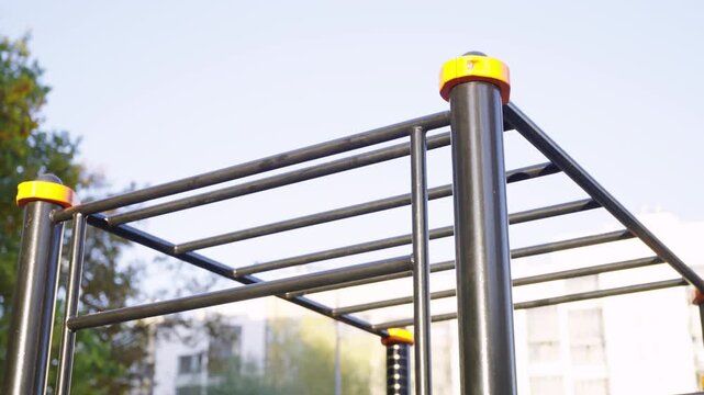 Monkey bars rise above workout zone in residential playground. Steel ladder supports climbing practice building upper body strength in yard