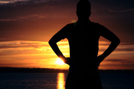 silhouette of a man near a lake during sunset