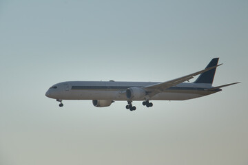 Fototapeta premium Large commercial airplane flying low during final approach phase, isolated against soft sky background with ample copy space for aviation, travel, and logistics concepts.