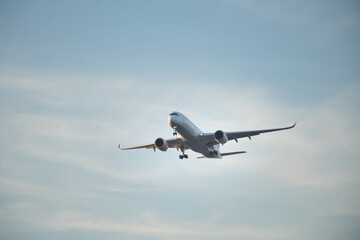 Fototapeta premium Modern twin engine passenger aircraft descending with landing gear deployed, captured from below against a calm sky, symbolizing travel, aviation industry, and global transportation.
