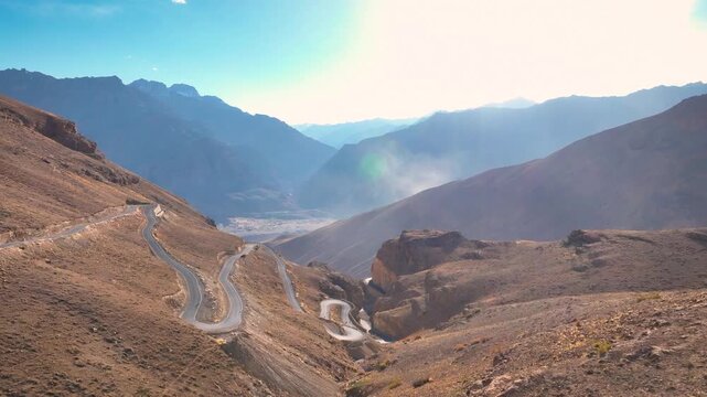 Epic drone view of a remote zigzag route traversing a steep, arid desert landscape in India.