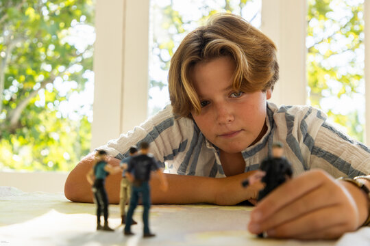 12 year old boy playing with toy soldiers at home