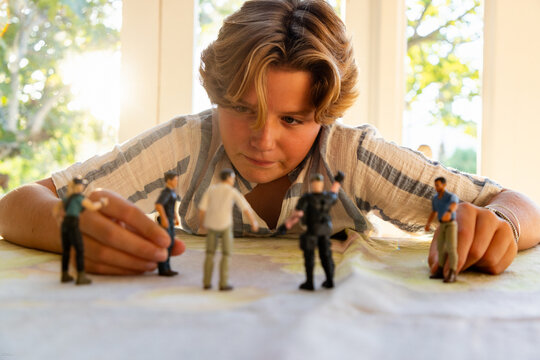 12 year old boy playing with toy soldiers at home