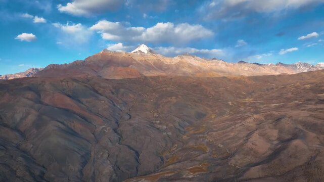 Cinematic aerial approach toward a majestic snow-capped Himalayan peak over barren desert terrain in Spiti Valley.