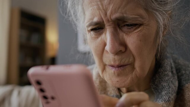 Extreme close-up of hands and face of distressed senior Caucasian woman browsing symptoms online on smartphone, while sniffling sneezing, coughing in hand and rubbing face due to flu virus