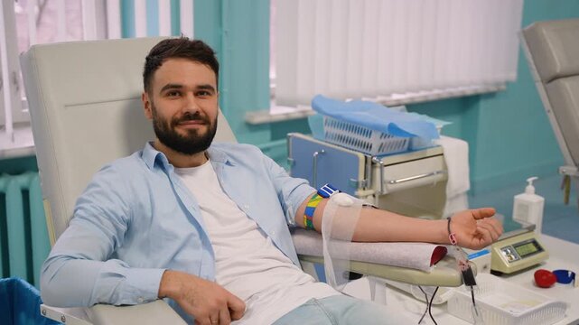 Male blood donor giving blood at donation center
