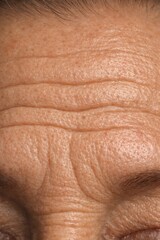 Naklejka premium Close-up of aged skin texture with visible wrinkles. Natural lighting enhances details and authenticity. Ideal for health and beauty concepts. Vertical image emphasizes skin condition.