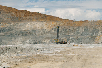 Fototapeta premium Drilling rig operating in large open pit mine landscape, gold mining industry
