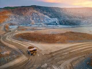 Aerial view Dump truck navigating curved mine road during sunset glow, gold mining industry © Parilov