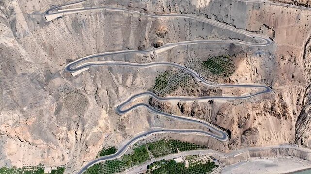 Top-down aerial aerial drone shot of the zigzagging Ka Loops mountain pass and highway in Himachal Pradesh, India.