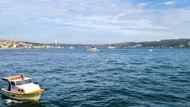 Scenic View of Istanbul Bosphorus with 15 July Martyrs Bridge, Moving Boats on Blue Sea, and Camlica Mosque on the Hill - Iconic Turkish Landmark and Maritime Traffic on a Partly Cloudy Day