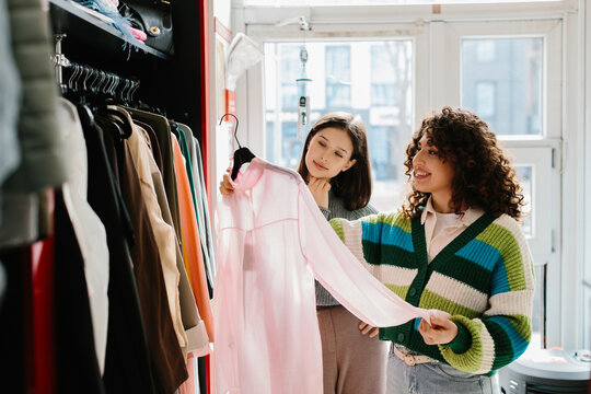 Young women shopping for clothes, discussing fashion