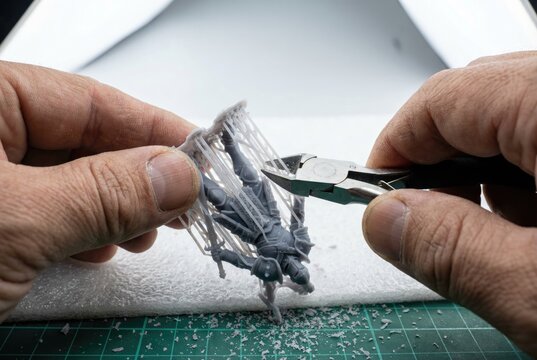 Using flush cutters to carefully remove support structures from a 3d printed resin miniature
