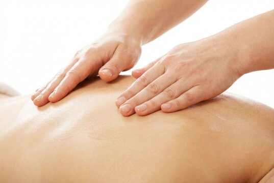 Close up of professional hands applying oil and massaging the bare back of a client