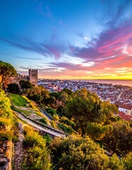 Obraz premium A vibrant sunset paints the sky over a historic city, viewed from a high vantage point with a castle