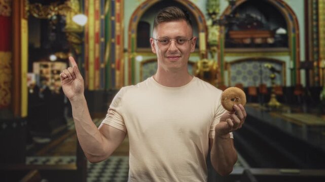 Man points finger with left hand and holds donut in right hand in ornate building interior; playful curiosity.