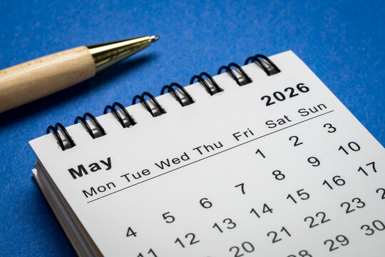 May 2026 - small spiral desktop calendar against art paper abstract, time and business concept