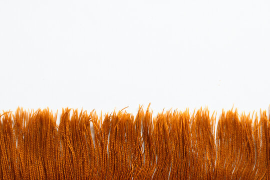 Macro shot of vibrant orange yarn fringe on decorative textile cloth
