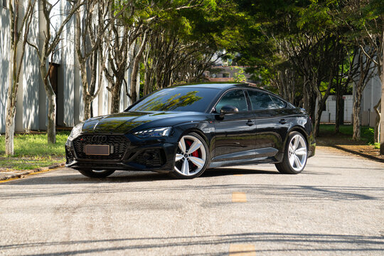 Black Audi RS5 front three quarters view on city street, High end luxury sportback car under trees
