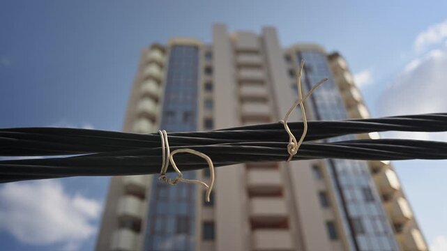 Close up of black electrical cables tied together with blurred modern building in background