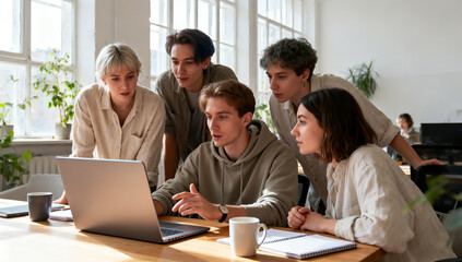 Fototapeta premium Group of young professionals discussing project ideas around laptop on wooden table.
