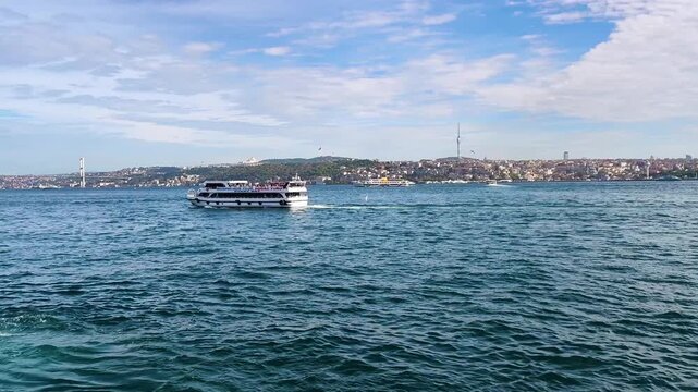 Scenic View of a Tourist Boat on the Bosphorus Strait in Istanbul with the 15 July Martyrs Bridge and Camlica Tower on the Horizon - Vibrant Maritime Traffic and Cityscape from Eminonu, Turkey
