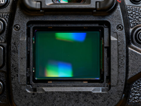 Professional digital camera sensor with iridescent light reflections, full frame CMOS imaging sensor inside DSLR body, modern photography hardware isolated on White Background