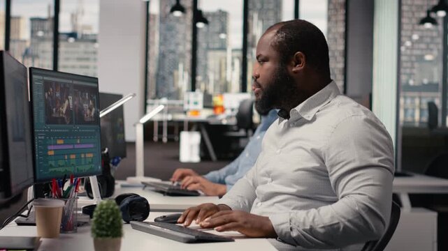 Portrait of african american man working on film montage editing, applying color grading and cutting raw clips for cinematic footage creation. Film engineer makes adjustments in post production.