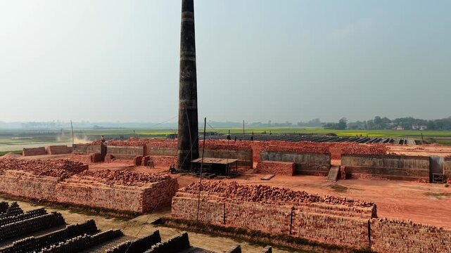 Brick factory yard with stacked bricks and industrial equipment outdoors in a rural setting site