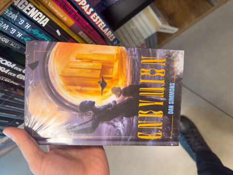 BELO HORIZONTE, MG, BRAZIL, MARCH 31, 2026. A person's hand grasps "Hyperion" by Dan Simmons, showcasing its epic science fiction cover art against a blurred background.