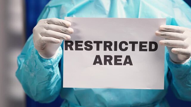 African healthcare worker in ppe holding a restricted area sign for safety