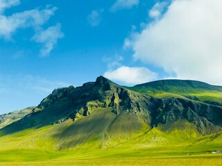 Fototapeta premium Green mountain landscape under blue sky with clouds