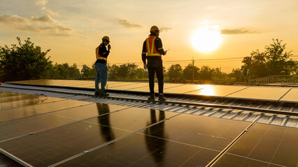 Silhouette of two engineers using a drone to inspect a solar panel roof at sunset. Professional team surveying renewable energy infrastructure during golden hour. © ultramansk
