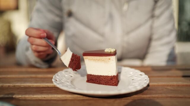 Close up of a layered chocolate cheesecake with creamy filling and chocolate glaze, being cut with a fork