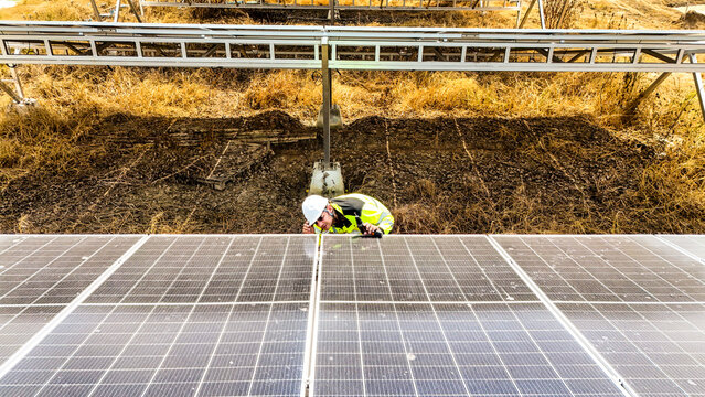 Close up of a technician carefully checking solar panel alignment. Professional working on a clean energy farm to generate sustainable electricity and protect the environment.