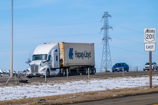 Calgary, Alberta, Canada. April 9, 2026. A Kenworth semi-truck hauls a Hapag-Lloyd shipping container along Stoney Trail on a sunny day.