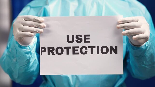 Healthcare worker wearing ppe holding sign encouraging safety and protection