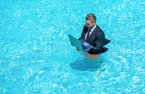 Businessman in suit with laptop in swimming pool. Crazy business man on summer vacation. Remote working. Summer business vacation. Funny crazy businessman rest in formal wear in pool, banner