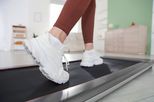 Sporty woman training on treadmill at home, closeup