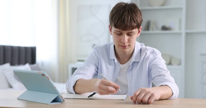 Teenage boy using tablet at wooden table indoors