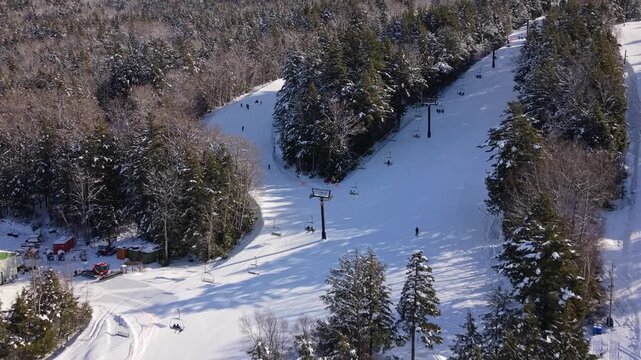 Drone aerial perspective: bright sunny winter day at Whistler Blackcomb. Skiers move across snow-covered trails in Nova Scotia Canada, stunning alpine landscape 4K.