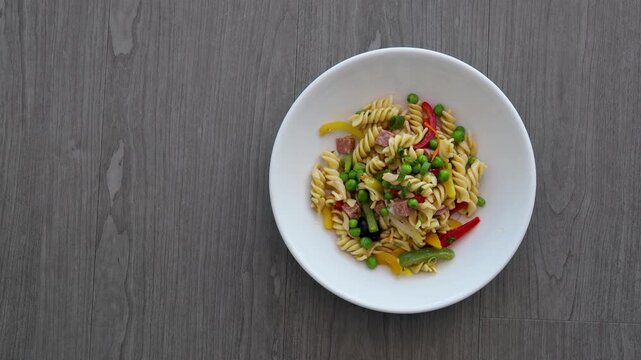 Eating a Bowl of Pasta Salad with Peas, Peppers and Ham