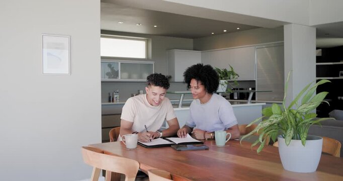 African American male partners reviewing papers at table in kitchen, signing to secure new home