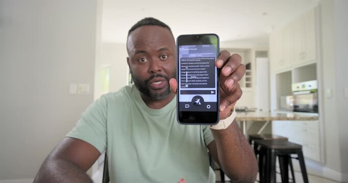 Mid-adult African American man in green tee and wristband, checking phone, explaining in kitchen