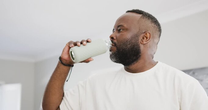 Vertical video: Lifting bottle to mouth, man in white tee sipping then checking bottle at home