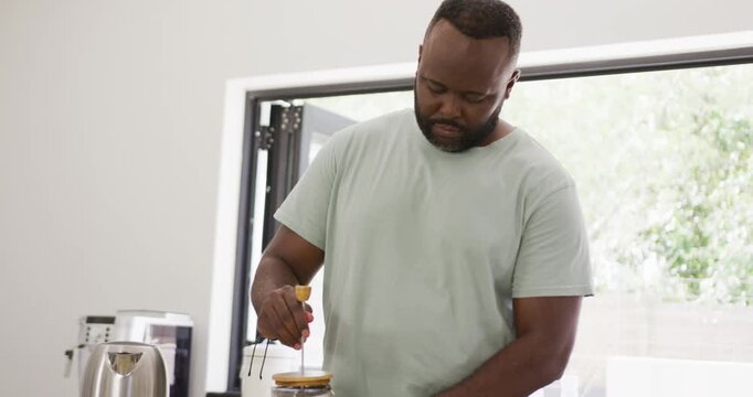 African American man pressing French-press plunger, finishing brew and preparing mug in kitchen