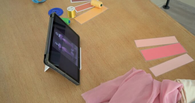 Camera panning across tabletop, revealing tablet playing plus pink swatches, scissors, tape, boxes