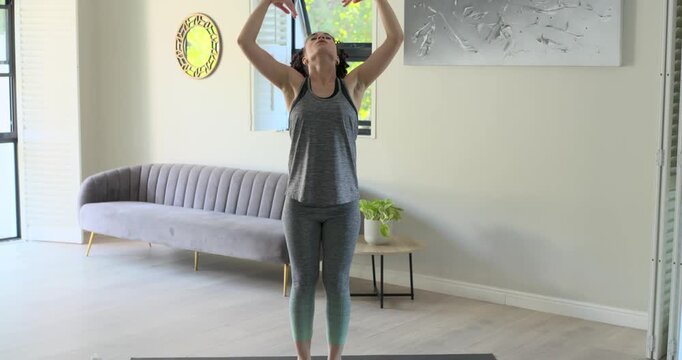 Forward folding woman in sportswear praying, shifting into tree pose on mat at home for balance