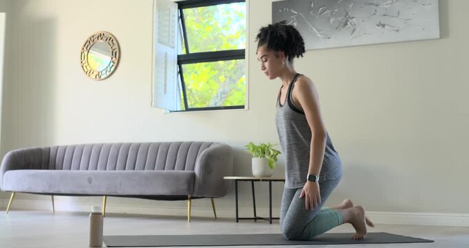 Vertical video: Woman entering living room flowing mat-cobra-child-pose opening chest in grey top